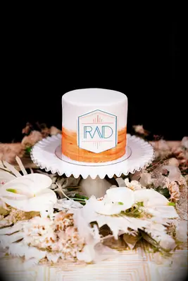 One-tier orange-and-white cake with modern monogram
