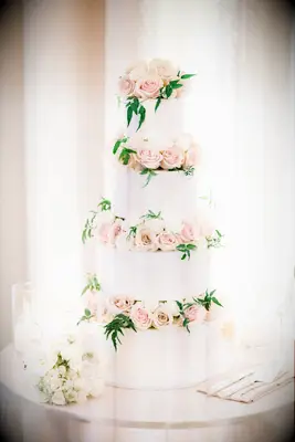 White four-tier cake with pink roses between each tier