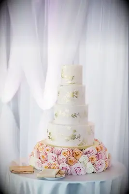 Gold-and-white wedding cake with fresh rose cake stand