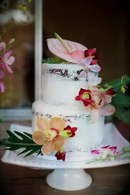 Semi-naked two-tier cake with tropical flower decorations