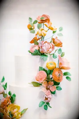 White tiered wedding cake with orange and pink flowers