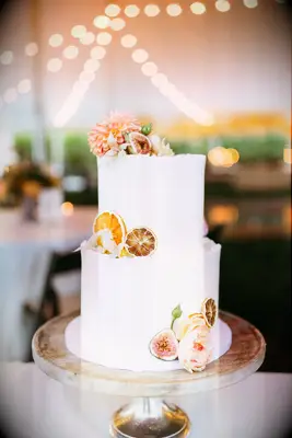 Tiered white wedding cake with preserved citrus and flowers