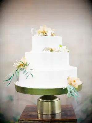 Minimal white three-tier wedding cake on gold cake stand