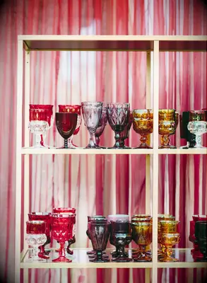 red, purple, pink and white glassware on a gold shelf at wedding reception