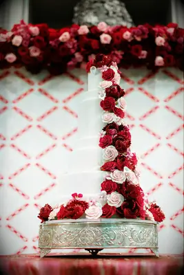 five tier fondant wedding cake decorated with pink and red roses down the side 