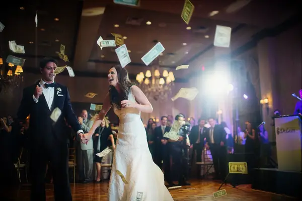 Couple laughs on the dance floor surrounded by dollar bills. 