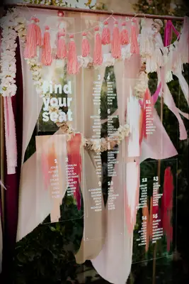 Acrylic seating chart hanging amongst boho pink decorations
