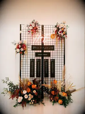 Black seating chart with neon sign and colorful flowers