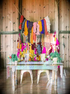 Colorful yarn backdrop at DIY bohemian wedding. 