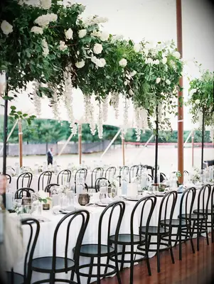 classic wedding tablescape with hanging greenery and white flower centerpiece above long table