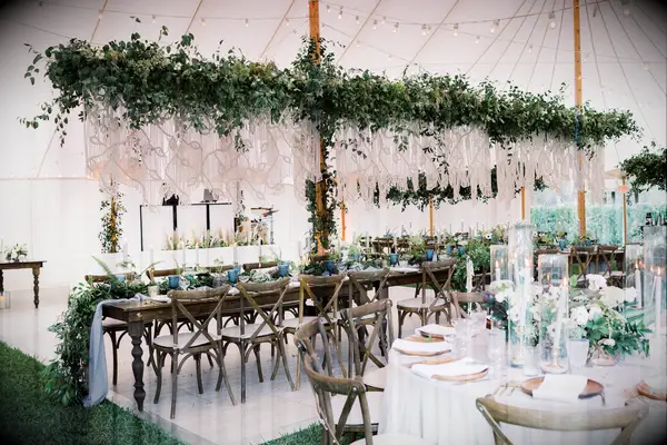 boho wedding reception tent with greenery garland and macrame ropes above long banquet table