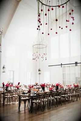 wedding barn venue with red long stem roses hanging upside down from round iron chandelier