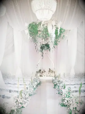 glam wedding ceremony with white and greenery flower chandelier with white drapery around the walls