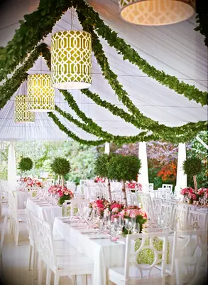 preppy indoor wedding reception decor with greenery garlands and green patterned lampshades hanging from white cloth tent ceiling
