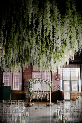 indoor wedding ceremony with white wisteria vines hanging from the ceiling