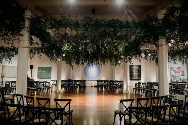 indoor wedding ceremony venue with chairs circling the altar and greenery vines covering the ceiling