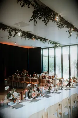 Long Reception Tables With Low Centerpieces, Gray Details and Hanging Greenery in Hotel