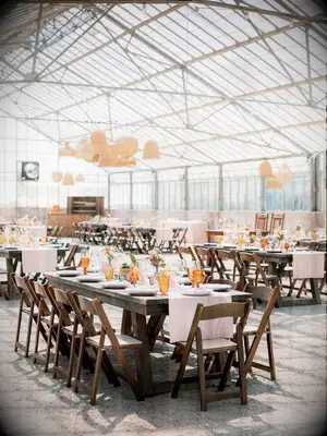 Greenhouse wedding with farm tables and wood chairs