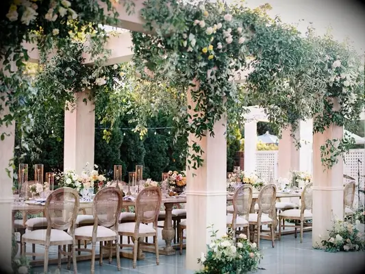 Classic wedding reception table with open-air structure covered in greenery