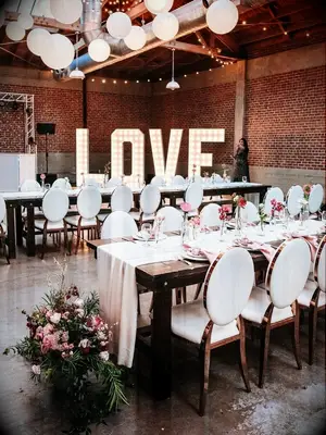 Modern wedding reception with white chairs, paper lanterns and marquee lights