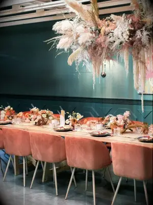 Eclectic wedding reception table with velvet chairs and pampas grass hanging installation