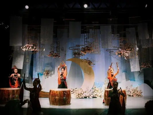 Drummers on stage with moon-inspired backdrop