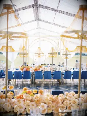 Tented wedding reception with beaded chandeliers and blue velvet chairs