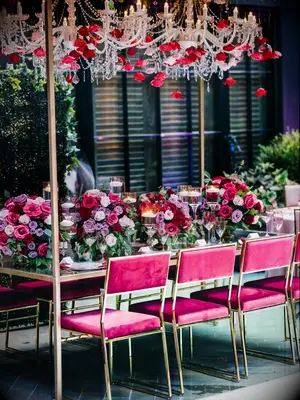 Glam hot pink wedding reception table with velvet chairs