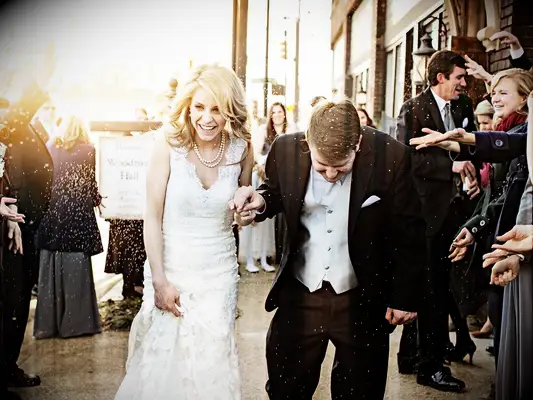 Bride and groom walking through rice toss after wedding ceremony. 
