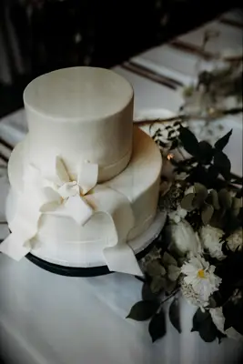 two tier white fondant wedding cake with white sugar bow and ribbon around the middle