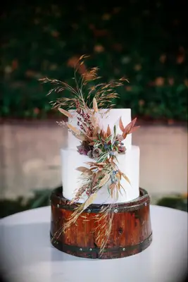 rustic two tier wedding cake decorated with bunny tails, sea oat grass stalks, autumn leaves and greenery