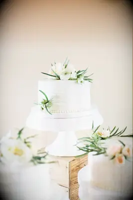 simple one-tier white buttercream wedding cake decorated with white flowers