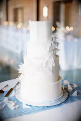 simple four tier white wedding cake decorated with miniature white paper airplanes