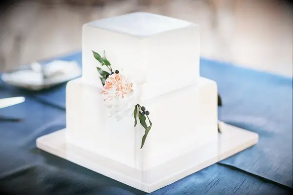 simple two tier square wedding cake with smooth white fondant and white sugar flower