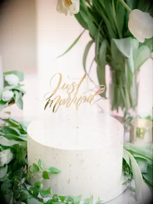 one tier simple wedding cake with smooth white buttercream and gold just married cake topper