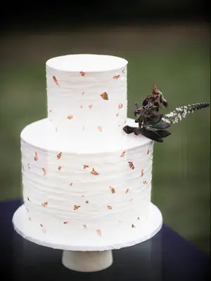 simple two tier buttercream wedding cake decorated with edible copper leaf pieces 