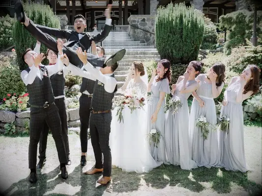 Funny groom and groomsmen photo with groomsmen throwing groom in the air