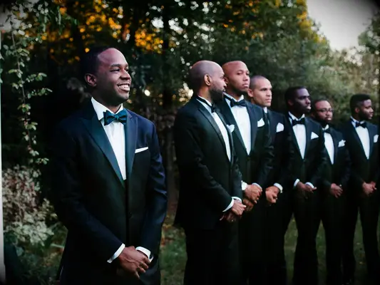 Groom smiling with groomsmen watching during wedding ceremony