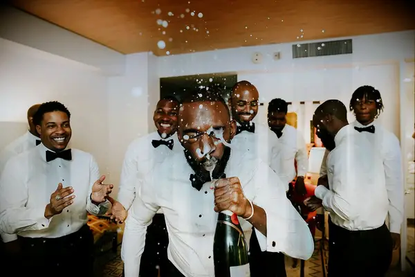 Groomsmen and Groom Getting Ready in Tuxes, Spraying Champagne in Groom