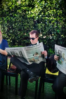 Groom Reading Custom Newspaper With Couple