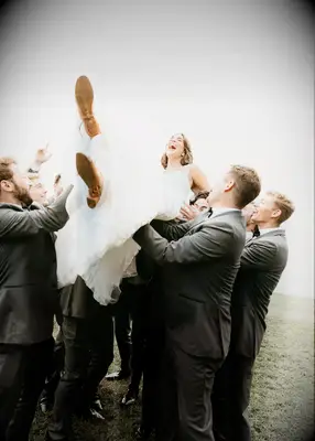 Groomsmen lifting up bride