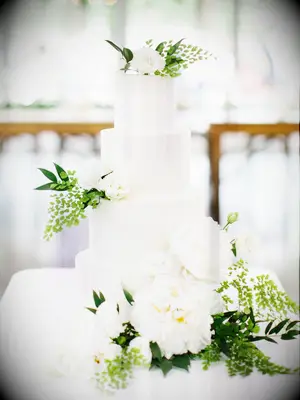 four tier white wedding cake with white peonies and greenery