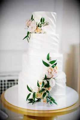 Four-Tier White Wedding Cake With Frosting Ridges and Fresh, Neutral Flowers
