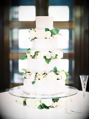 white four tier wedding cake with blush and ivory roses in between each tier