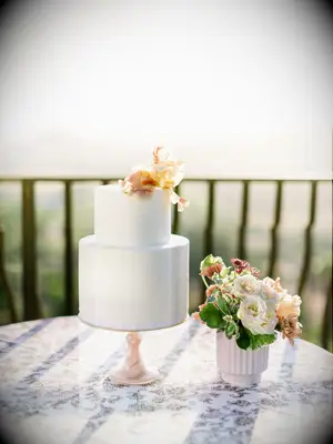 two tier white wedding cake with peach iris on top