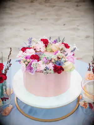 one tier pink wedding cake with halo of flowers and macarons on top