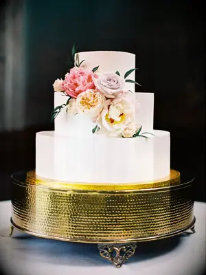 three tier smooth buttercream wedding cake with pale yellow, pink and lilac roses