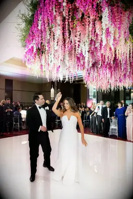 A couple dance beneath a stunning floral chandelier.