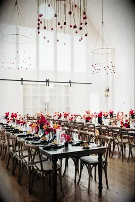 The tables are set in this glowing white space with vibrant floral centerpieces in gold, wine and pink.