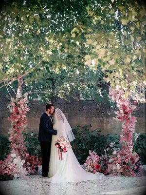 A couple share a tender moment among their dusty rose wedding ceremony decor.